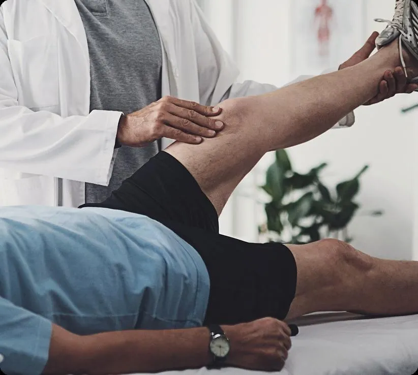 Healthcare professional examining patient's leg during physical therapy or medical consultation session.